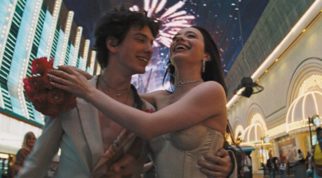 A young couple walk through Las Vegas underneath fireworks.