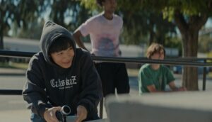 A teen boy holds up a small video camera at a skate park.