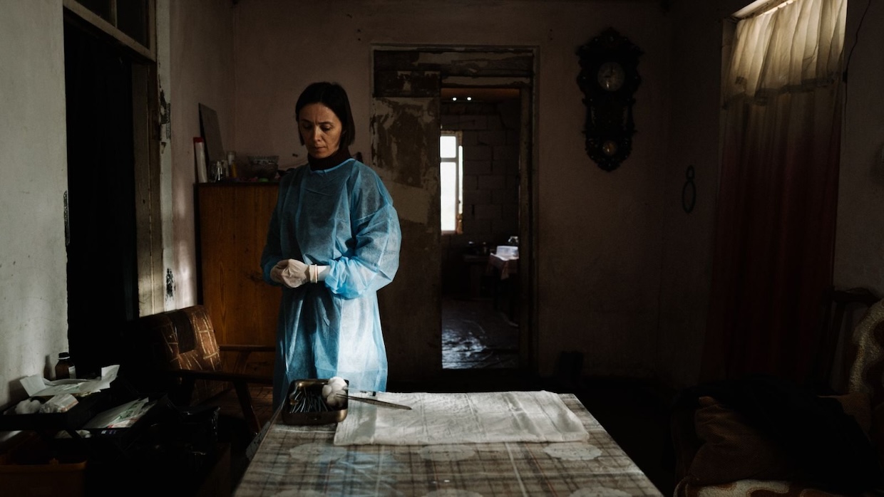 A woman in blue clothing stands in front of a table covered with newspapers.