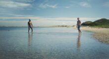 Two men are on a sunny beach.