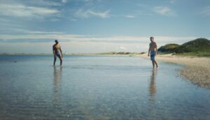 Two men are on a sunny beach.