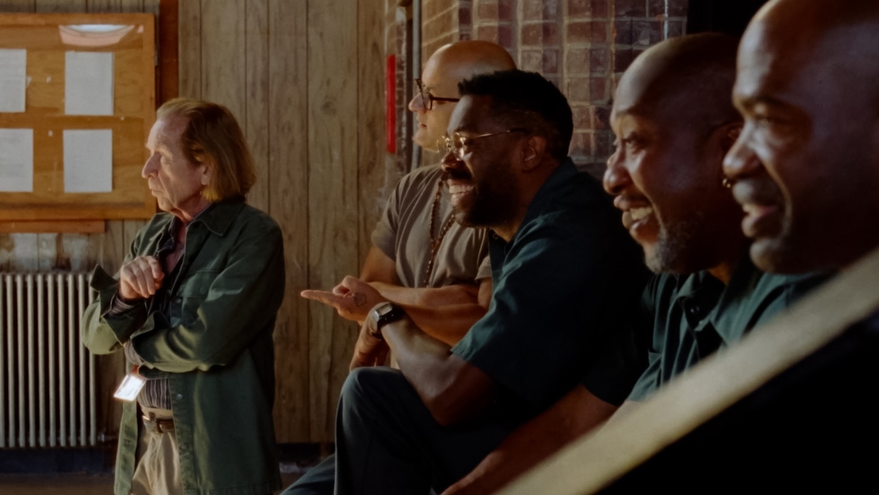 A group of men smile while incarcerated.