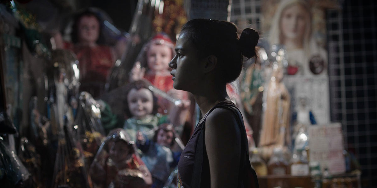 A young gymnast stands at night before a display of dolls.