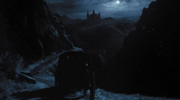 A carriage drives towards a gloomy castle on a moonlit night.