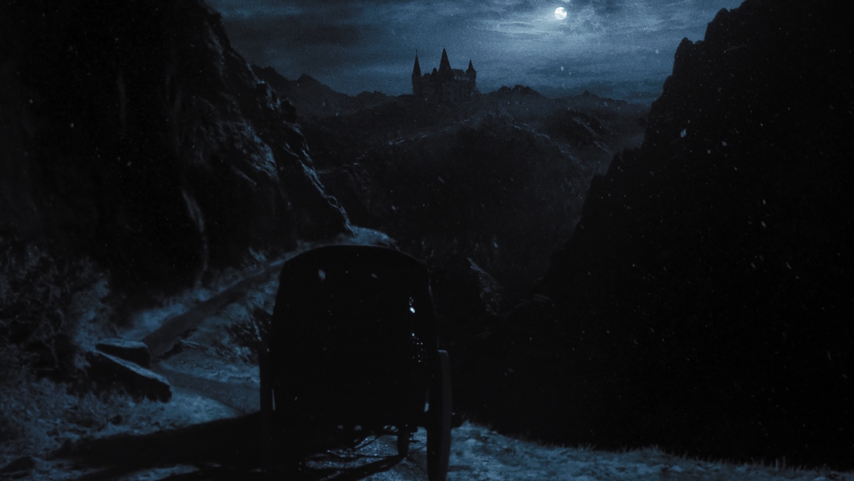 A carriage drives towards a gloomy castle on a moonlit night.