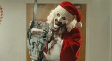 A clown in a Santa suit wields a chainsaw.