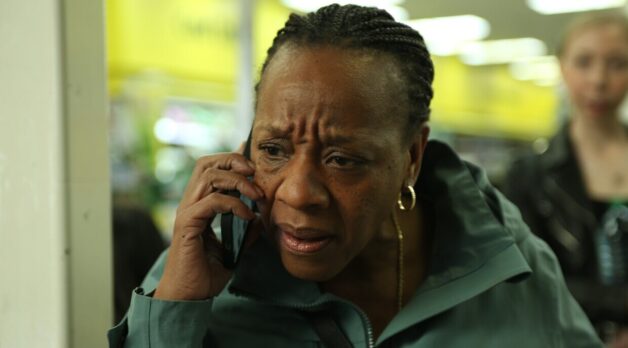 A woman, looking concerned, speaks into a cellular phone.