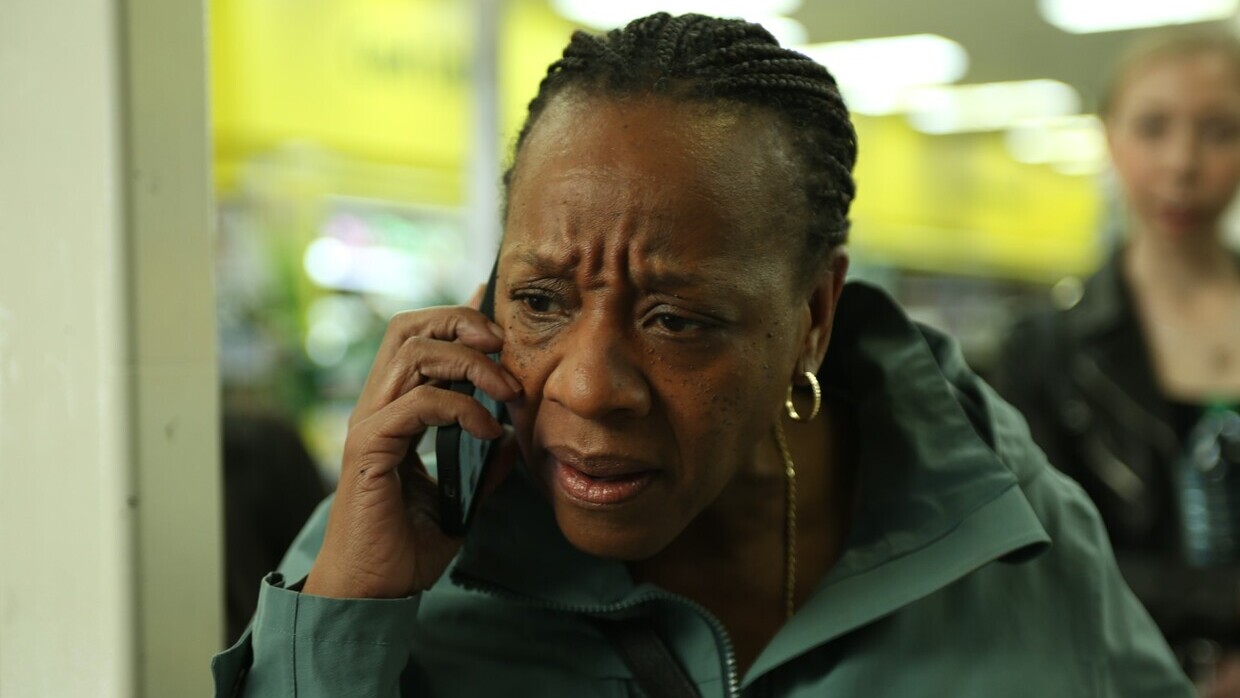 A woman, looking concerned, speaks into a cellular phone.