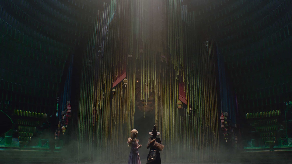 Two witches—one good, one bad—stand on an enormous set.