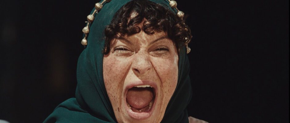 A woman with a green scarf around her head is screaming.