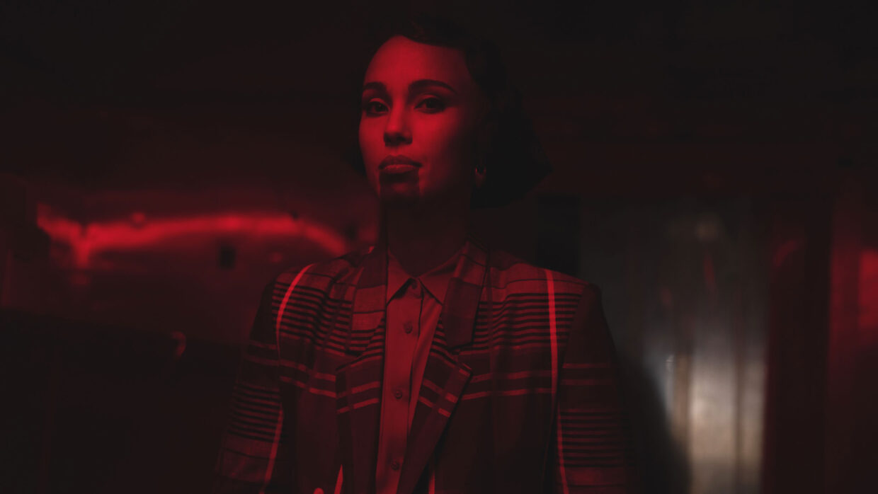 A well-dressed woman is bathed in red light.