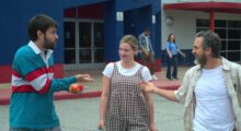 Two white men and a white woman are looking at one another and laughing.