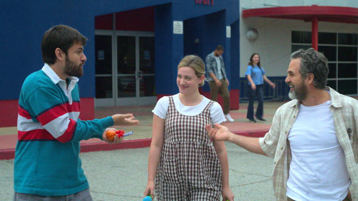 Two white men and a white woman are looking at one another and laughing.