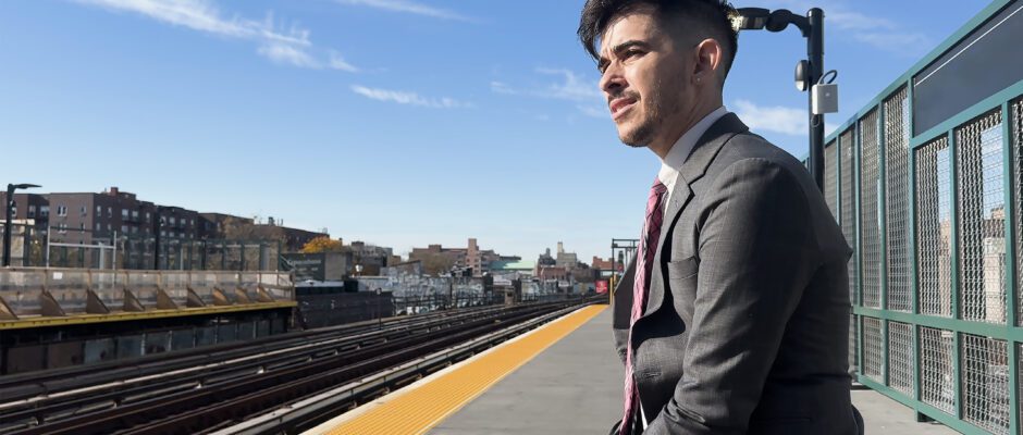 A young man in a suit is waiting at a train station.