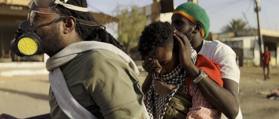 Three Sudanese wearing masks are in the streets.