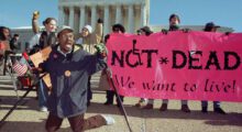 A disabilities rights protest with a banner reading "Not Dead, We Want To Live" visible.