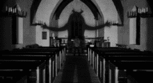 The gigantic shadow of a devil with horns covers a man in a church.