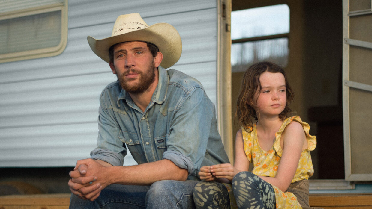 A white man and a young white girl sit outside a home.