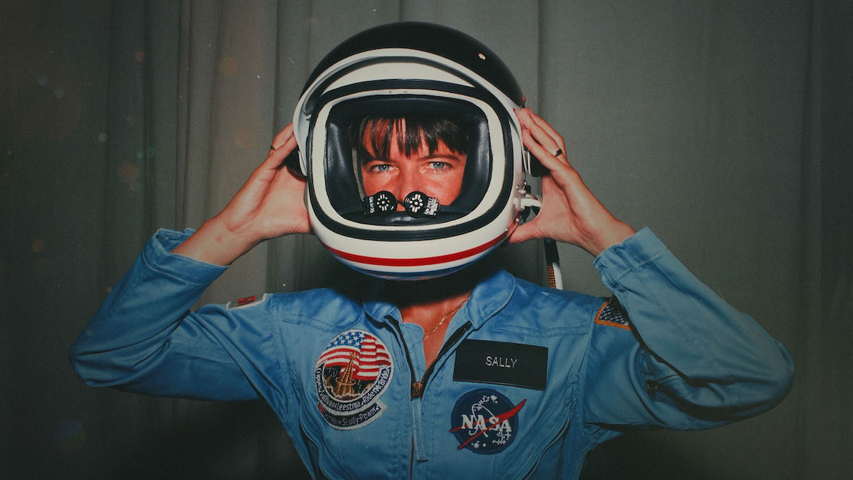 Astronaut Sally Ride wears a blue jumper and space helmet.