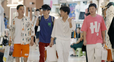 Four Asian men in colorful attire walk toward the camera.