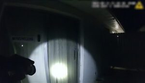 A flashlight is shining onto a wall in an otherwise pitch-black room.