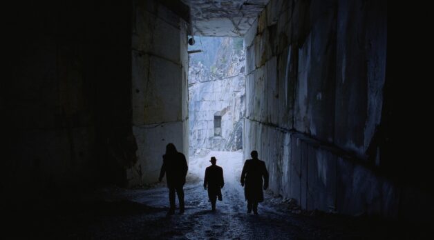 Three men walk into a gleamingly white marble quarry.