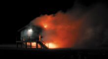 An elevated house on fire in the night.