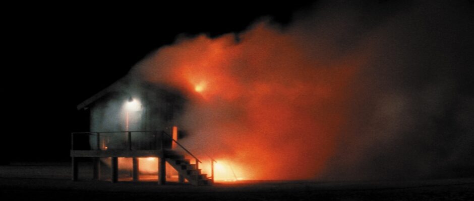 An elevated house on fire in the night.