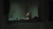 A woman sits in a bath.
