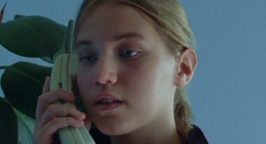 A young girl talks on a cordless telephone.