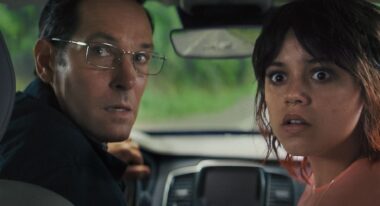 A father and daughter give big looks directly to camera in a car.