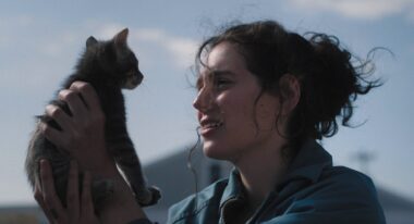 A woman holds a cat while standing outside.