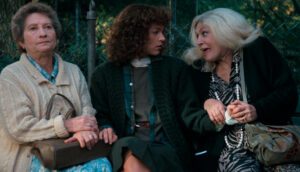 Three women sit on a park bench.