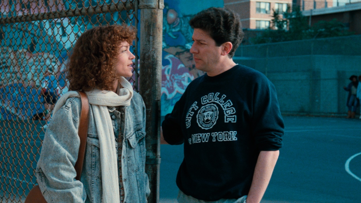 A man and a woman talk to each other outside of a basketball court.