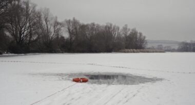 An inner tube rests next to a small pool of water within a larger frozen-over lake.