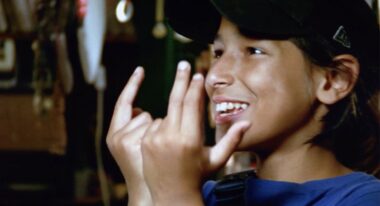 A young boy holds his hands and makes signs.
