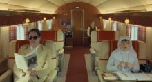Three people sit on an elaborate, expensive private airplane.