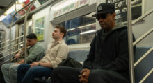 Three men sit in a New York subway car.
