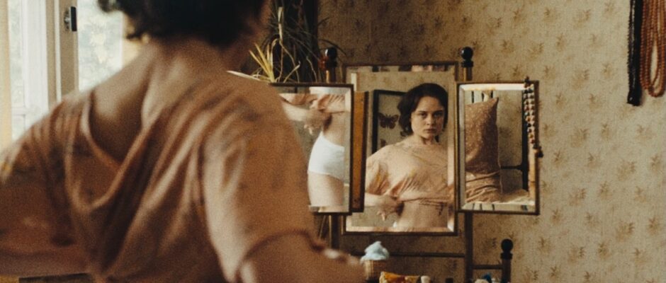 A young woman adjusts her crop top in front of a mirror.
