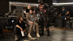 A group of people on a film set, one of whom is in a superhero costume.