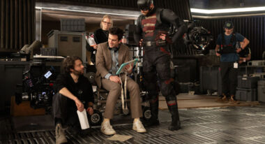 A group of people on a film set, one of whom is in a superhero costume.