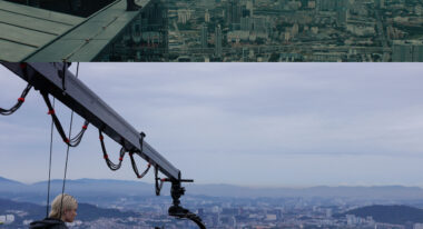 Two images of a woman on the ledge of a roof high above a cityscape, the second of which also includes a camera pointed at her.