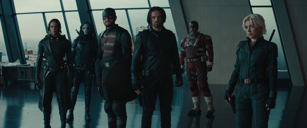 A group of superheroes stand in a lobby.