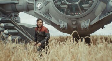 A man in a wheatfield with a spaceship behind him