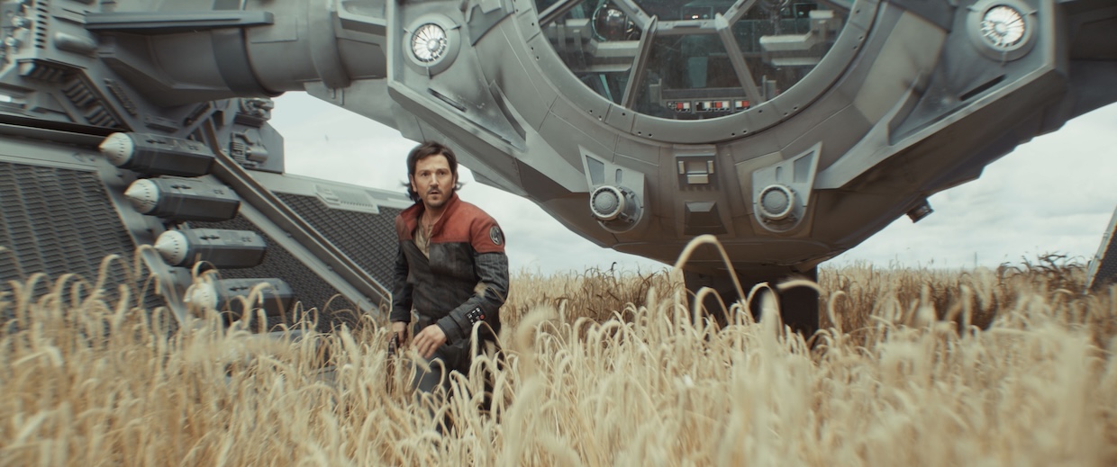 A man in a wheatfield with a spaceship behind him